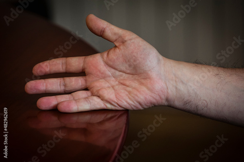 A man's right hand open and leaning on a table
