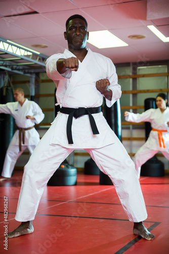 African-american man exercising kata moves during group kimono training.