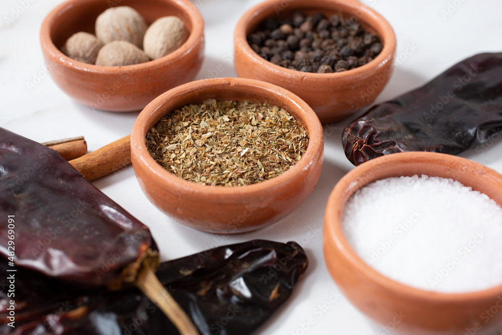 A view of a condiment cup of dried oregano flakes, among other herbs and spices. A view of a condiment cup of dried oregano flakes, among other herbs and spices.