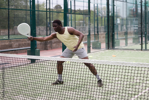 African american man playing paddle tennis on the padel court © JackF