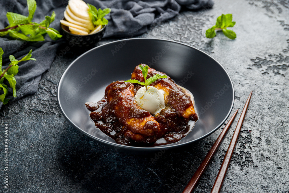 Fried bananas with ice cream on black bowl, Chinese cuisine Fried bananas with ice cream on black bowl, Chinese cuisine