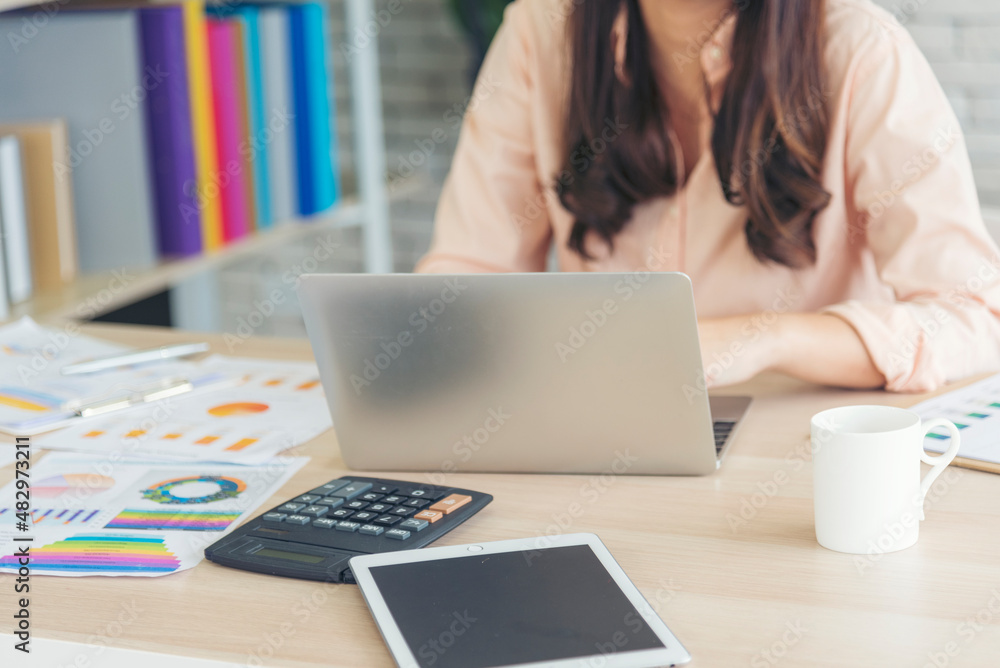 Asian Female freelance using laptop at home office desk. Woman reading financial graph chart Planning analyzing marketing data. Asian female people working office firm with business stuff, coffee cup Asian Female freelance using laptop at home office desk. Woman reading financial graph chart Planning analyzing marketing data. Asian female people working office firm with business stuff, coffee cup