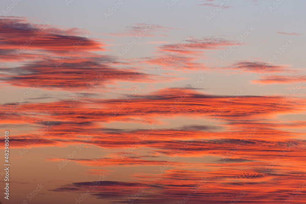 Fototapeta premium Dramatic sunset sky with saturated orange clouds with sunlight.