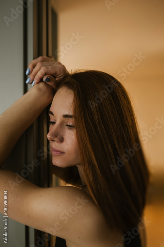 large vertical portrait of a young woman with clear skin and thick red hair to her shoulders. selective focus