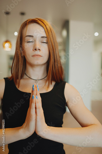 young woman with bright red hair does yoga in stylish modern apartment. woman slender muscular body . yoga basic asanas. home independent training. selective focus, vertically photo