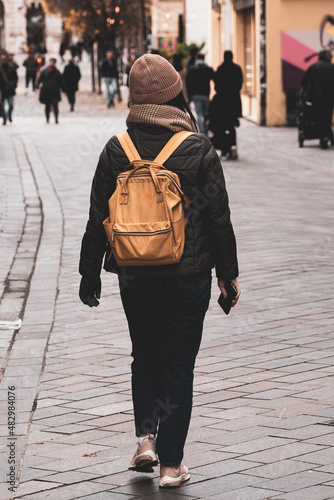 Photography Bundled up Girl with Yellow Backpack Walks Through Pedestrian Street