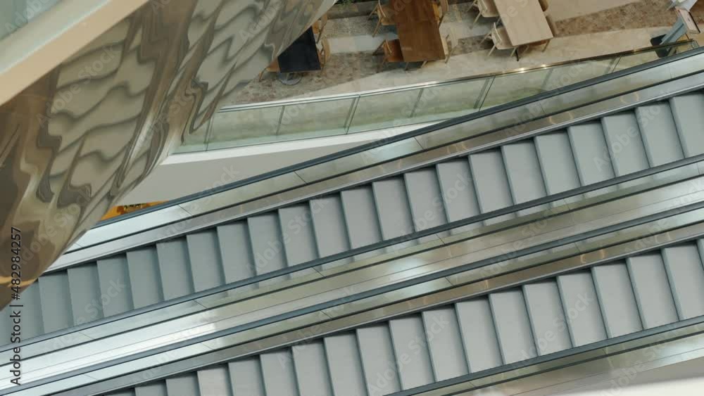 Top View and slow motion of beautiful metal escalator is moving in department store or train station with beautiful sun light, it shows concept of transportation for urban life in the city. Top View and slow motion of beautiful metal escalator is moving in department store or train station with beautiful sun light, it shows concept of transportation for urban life in the city.