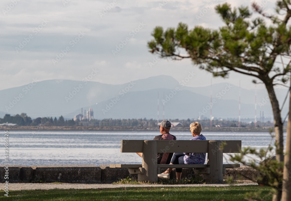 Elderly couple enjoying the afternoon on a calm and peaceful relaxing in front of the ocean view.