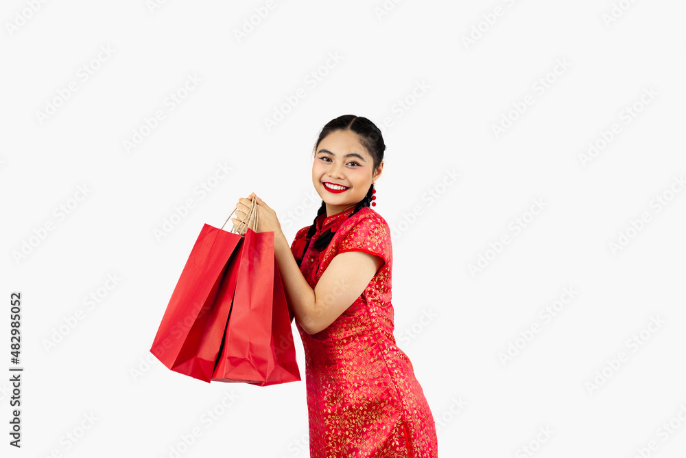 Asian girl in red traditional oriental costume holding shopping bags isolated on white background. Chinese new year in shopping concept style. Asian girl in red traditional oriental costume holding shopping bags isolated on white background. Chinese new year in shopping concept style.