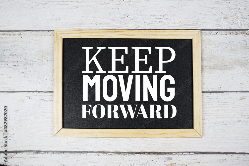 Obraz premium Keep Moving Forward word on blackboard on wooden background