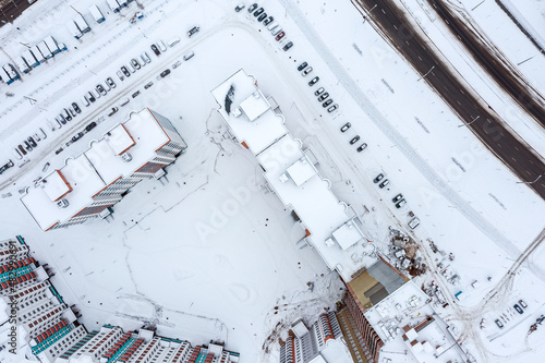 aerial view of the courtyard of a high-rise residential building. snow-covered cars and streets in winter city.