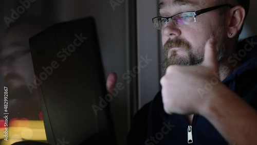 Adult man received good news, looking at laptop screen. Male victorious hand gesture. Web leisure at night time, online sweepstakes concept.