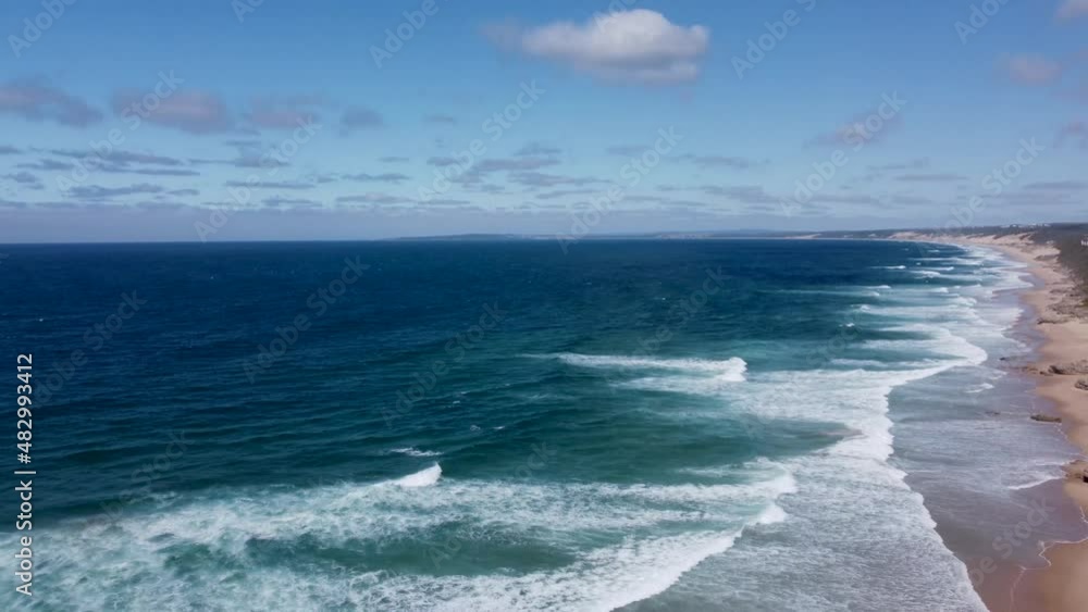 Long open sandy beach with small waves rolling onto the sand deep blue water to the horizon camera panning down from the horizon Long open sandy beach with small waves rolling onto the sand deep blue water to the horizon camera panning down from the horizon