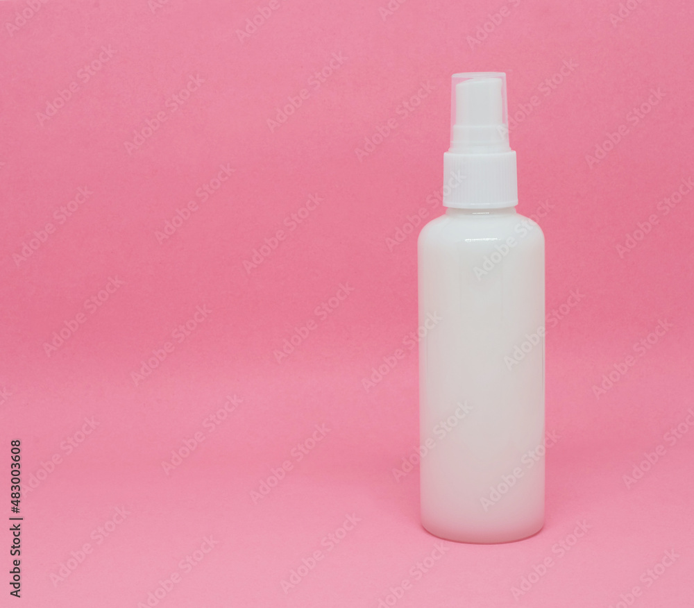 A spray bottle filled with liquid on a pink background A spray bottle filled with liquid on a pink background