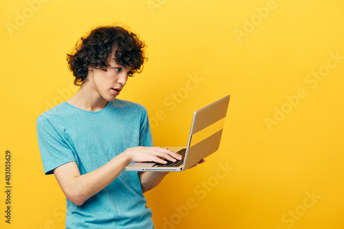 curly guy with laptop work online finance yellow background