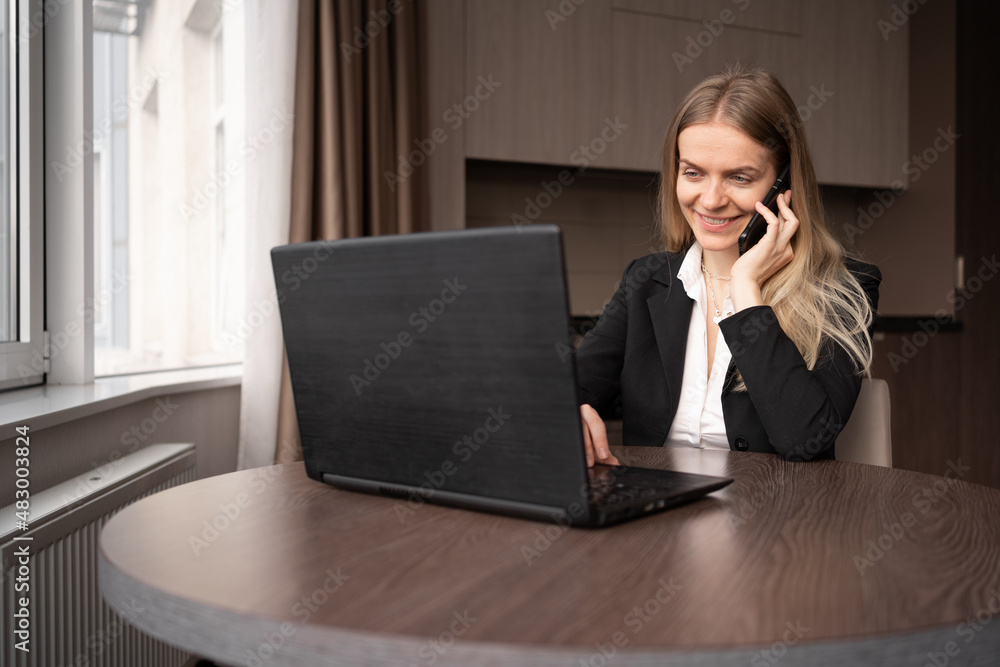 Shot of an attractive young businesswoman working on a laptop at her workplace, a woman talking on a mobile phone in office, online store consultant Shot of an attractive young businesswoman working on a laptop at her workplace, a woman talking on a mobile phone in office, online store consultant