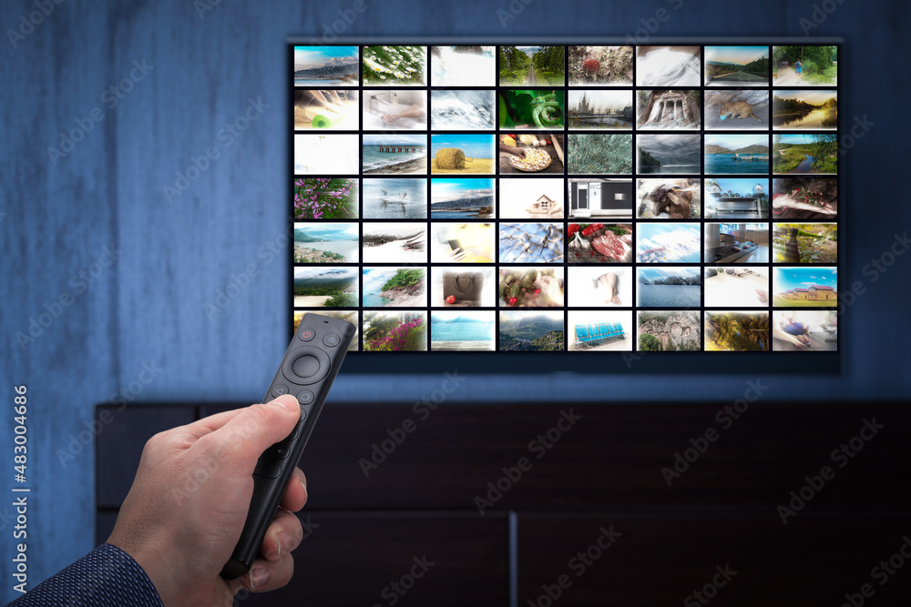 Video on demand service on smart TV. man choosing what to watch on TV at home. Video on demand or VOD. Online movie stream service in smart tv. Male hand holding TV remote control. Video on demand service on smart TV. man choosing what to watch on TV at home. Video on demand or VOD. Online movie stream service in smart tv. Male hand holding TV remote control.
