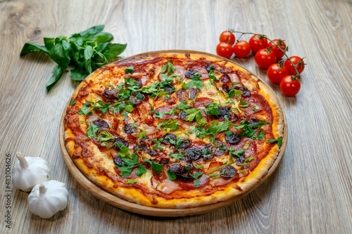 pizza with sausage, ham, salami, tomato sauce and parsley