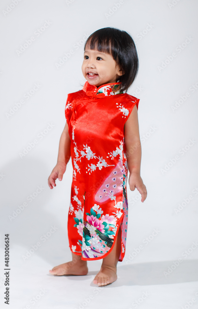 Studio shot of little cute innocent Asian kindergarten preschooler daughter girl kid model short black hair in red Chinese traditional qipao Cheongsam outfit standing alone on white background. Studio shot of little cute innocent Asian kindergarten preschooler daughter girl kid model short black hair in red Chinese traditional qipao Cheongsam outfit standing alone on white background.