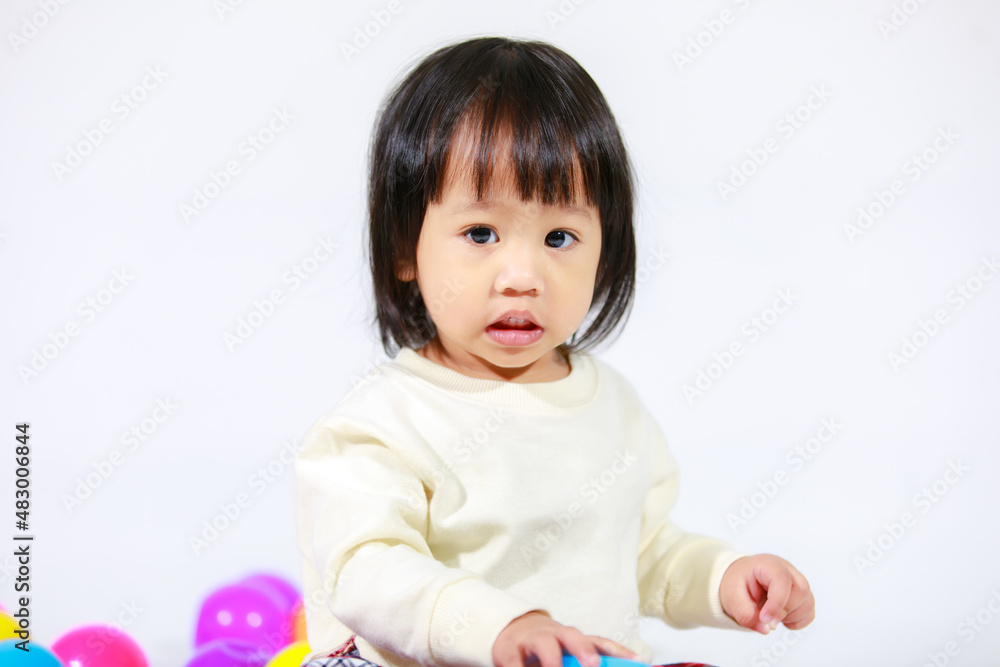 Studio shot of little cute short black hair Asian baby girl daughter model in casual plaid skirt sitting on floor smiling laughing playing with colorful round balls toy alone on white background Studio shot of little cute short black hair Asian baby girl daughter model in casual plaid skirt sitting on floor smiling laughing playing with colorful round balls toy alone on white background