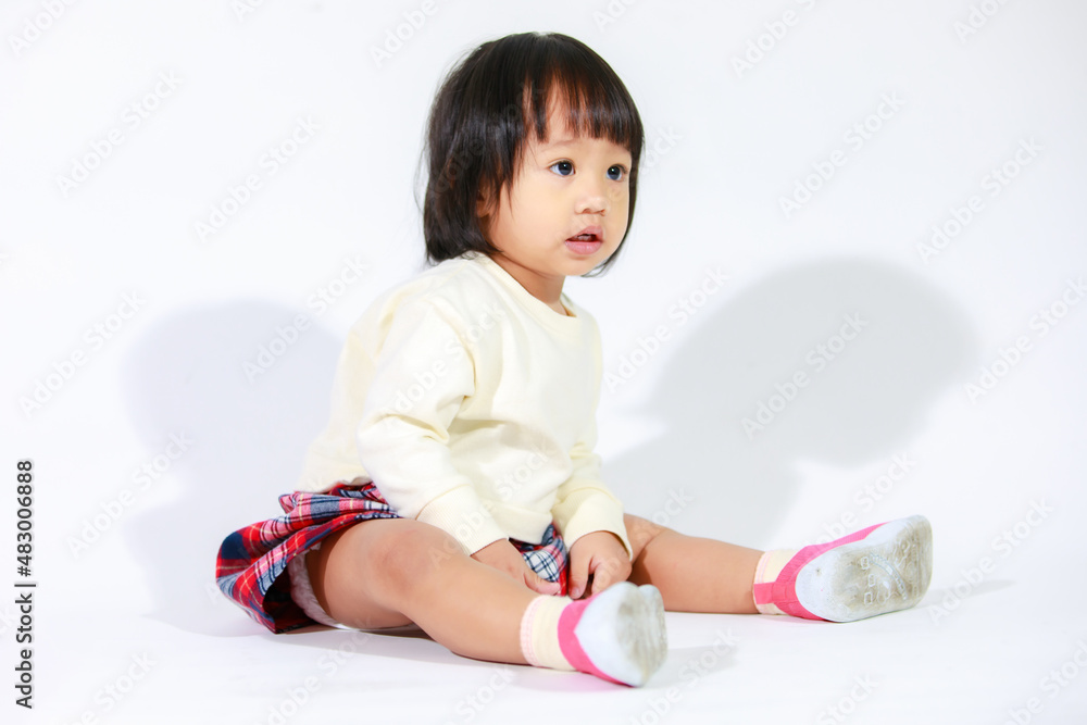 Naklejka premium Studio shot of little cute short black hair Asian baby girl daughter model in casual plaid skirt sitting and smiling on white background