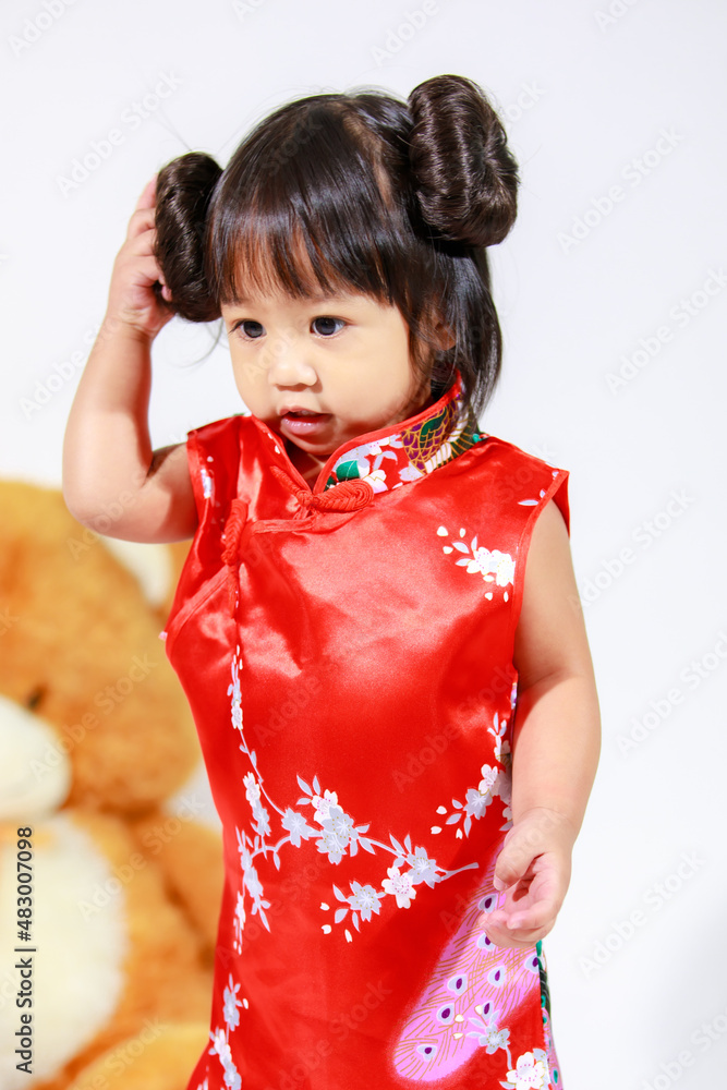 Studio shot of little cute innocent Asian kindergarten preschooler daughter girl kid model with bun hairstyle in red Chinese traditional qipao Cheongsam outfit standing alone on white background Studio shot of little cute innocent Asian kindergarten preschooler daughter girl kid model with bun hairstyle in red Chinese traditional qipao Cheongsam outfit standing alone on white background