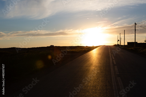An asphalt road stretching into the distance at sunset