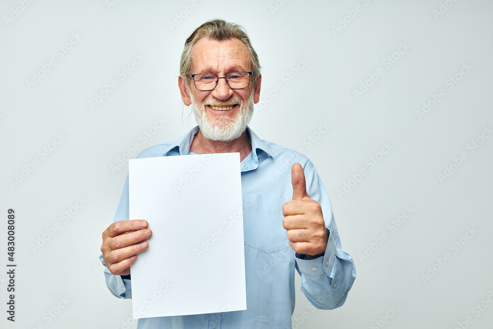 Senior grey-haired man in a blue shirt and glasses a white sheet of paper cropped view Senior grey-haired man in a blue shirt and glasses a white sheet of paper cropped view