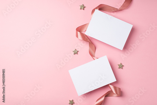 Top view photo of valentine's day decorations curly silk ribbon glowing stars and two letters on isolated pastel pink background with copyspace