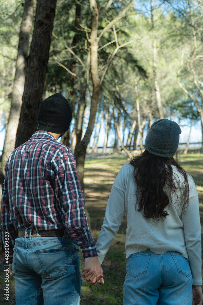 Fototapeta premium Back of a young couple during a trekking day in the wood