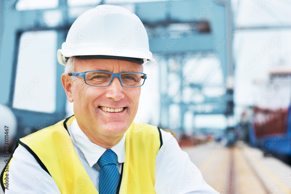 Safety first. Portrait of a dock worker standing at the harbor amidst shipping industry activity. Safety first. Portrait of a dock worker standing at the harbor amidst shipping industry activity.