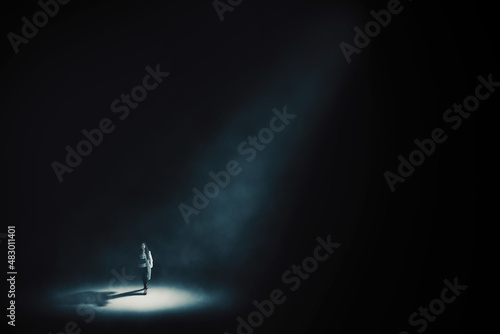 Businesswoman walking under light in dark room