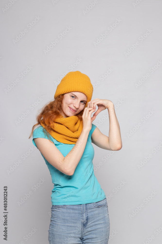 red-haired girl in a warm hat on a light background red-haired girl in a warm hat on a light background