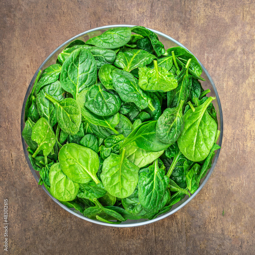 Bowl of Spinach leaves on wooden table. Fresh Spinach Closeup. Top view. .