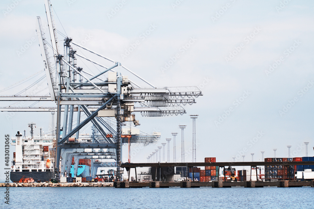 Gantry Cranes in a harbor. A photo of a harbor with anchored ships, gantry cranes and containers..