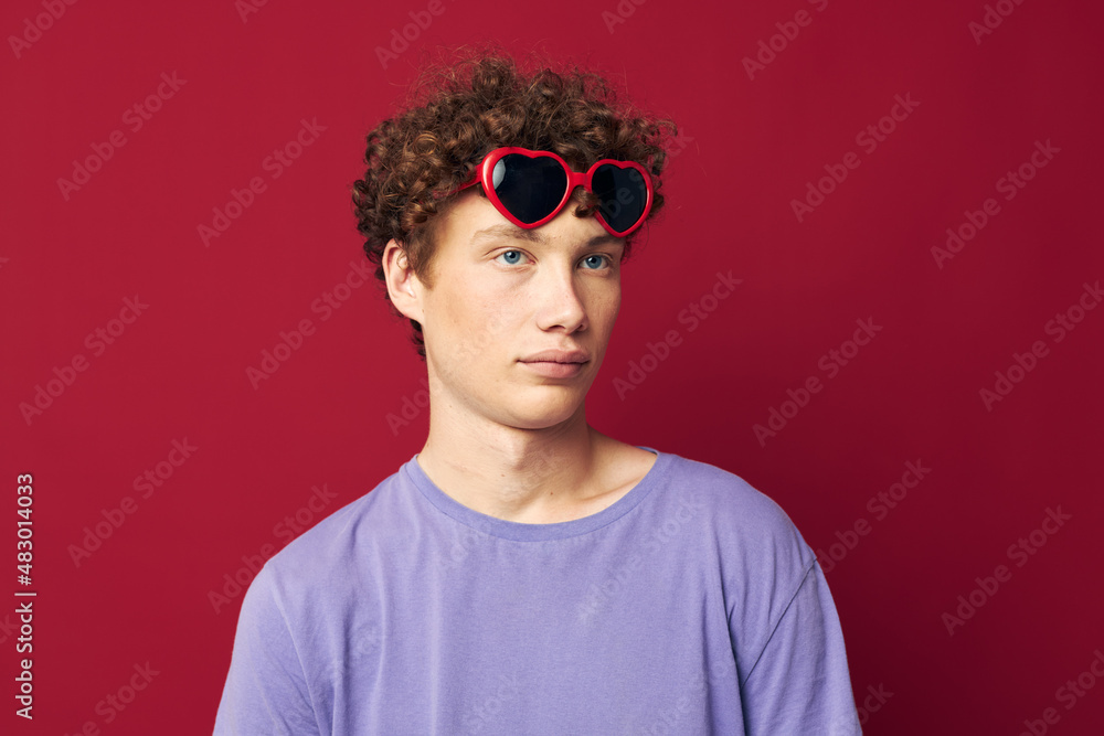 portrait of a young curly man guy in a purple t-shirt with sunglasses posing isolated background portrait of a young curly man guy in a purple t-shirt with sunglasses posing isolated background