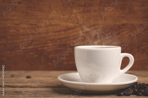 White cup with hot coffee on wooden table