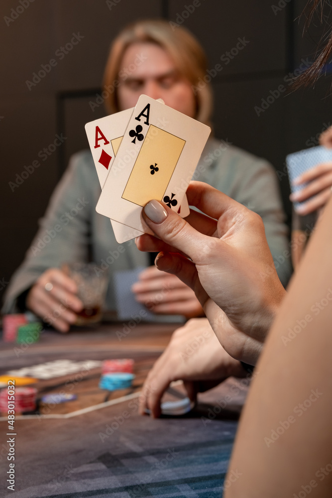 Two aces in hand of woman playing poker at gaming table