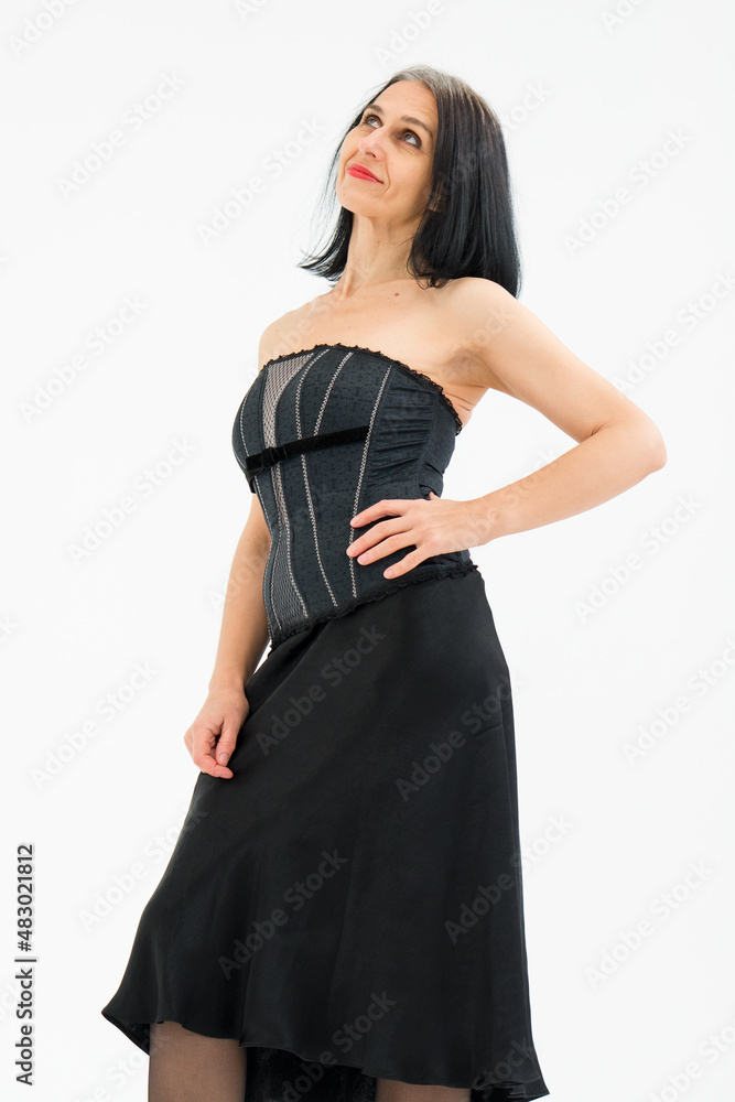 Middle aged woman starting getting grey-haired is posing in studio in black clothes and stockings on white background, middle age sexy lady, cosmetology concept Middle aged woman starting getting grey-haired is posing in studio in black clothes and stockings on white background, middle age sexy lady, cosmetology concept