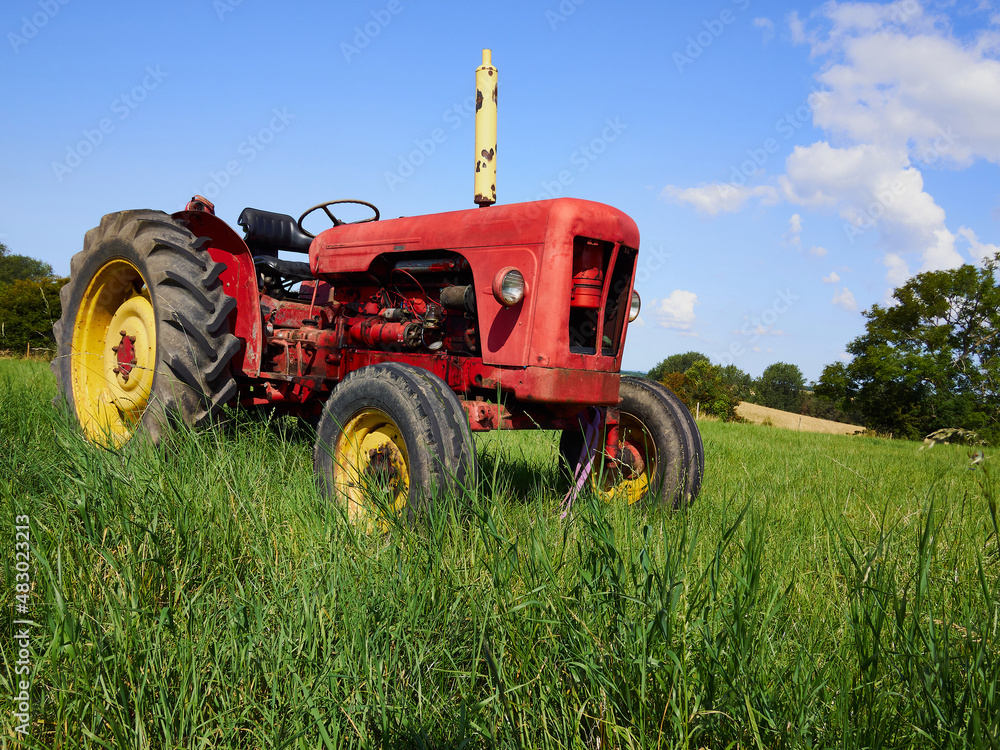 Red old tractor standing in a green field Red old tractor standing in a green field