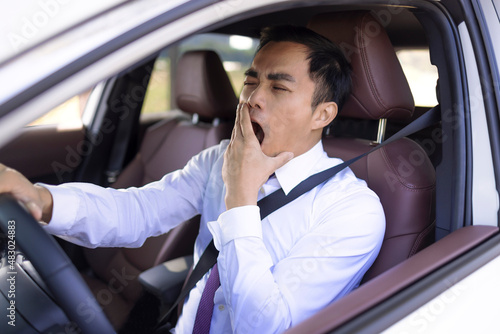 Business man looks tired yawning while driving the car photo