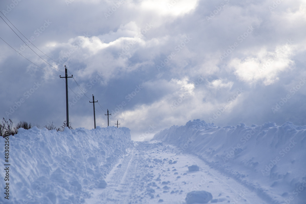 A deserted country road through snow-covered fields. Poor visibility due to a snowstorm. A deserted country road through snow-covered fields. Poor visibility due to a snowstorm.