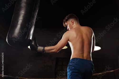 A male boxer is training in the gym view from the back.