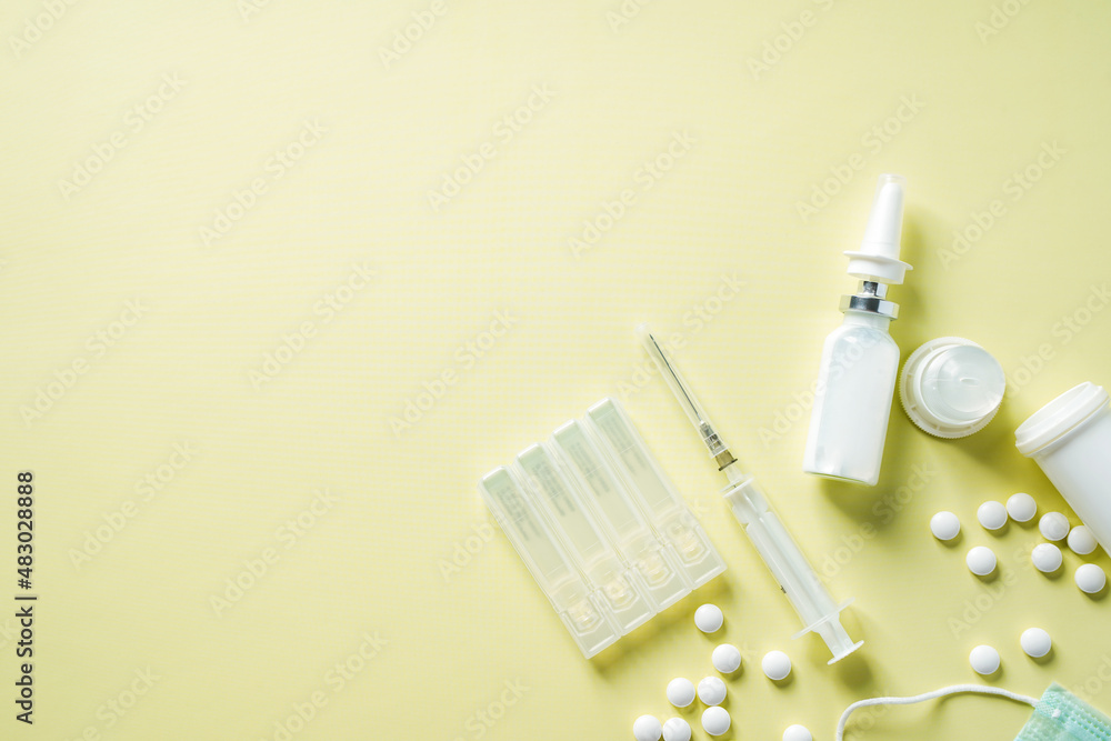 Medicine background with packs of pills, glass bottle, medical masks and ampoules on the beige background with copy space