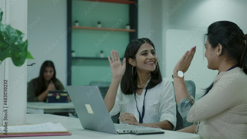Two office Asian workers talking in office,young Indian colleagues discussing work on a laptop computer in co-working space, corporate Indian business people looking at a laptop having conversation.