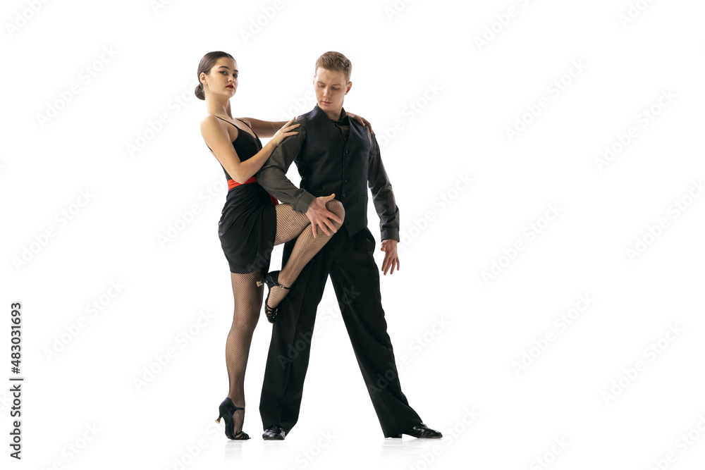 Beautiful sportive young man and woman dancing Argentine tango isolated on white studio background. Artists in black stage costumes Beautiful sportive young man and woman dancing Argentine tango isolated on white studio background. Artists in black stage costumes