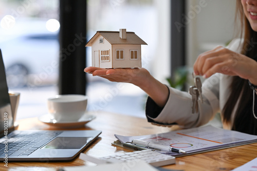 Estate agent holding house model and house key in hand. Mortgage Real estate investment and insurance concept. photo