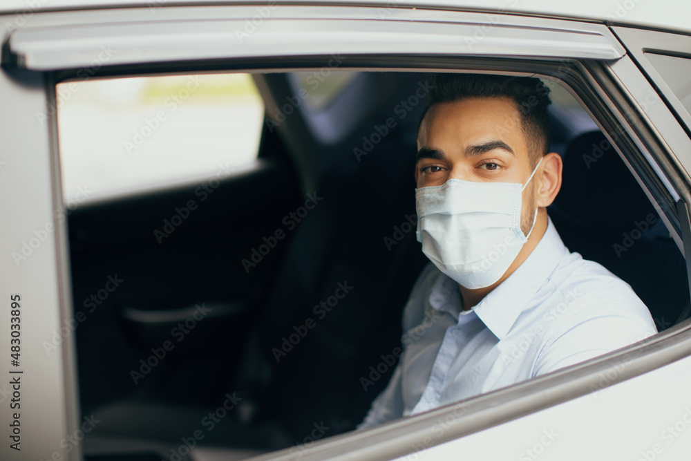 Middle-eastern man in protective face mask sitting at taxi Middle-eastern man in protective face mask sitting at taxi