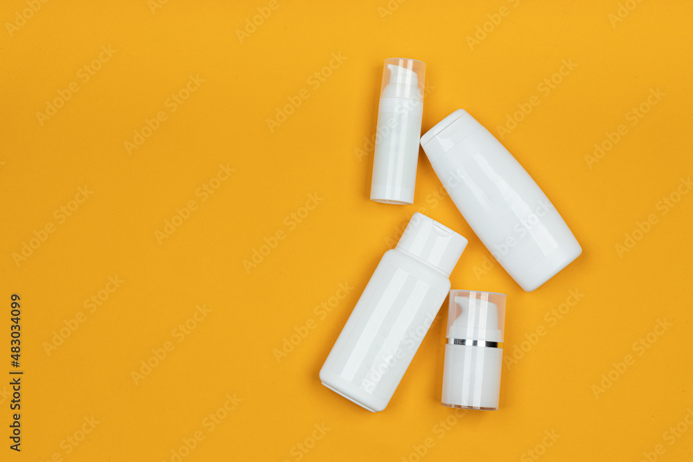 White jars and containers of cosmetics on yellow background. Skincare product set. Face and body care concept. White jars and containers of cosmetics on yellow background. Skincare product set. Face and body care concept.