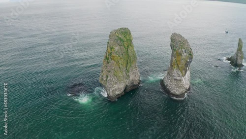 Circle sea panorama. Huge cliffs towering in teal water, seagulls flying around
